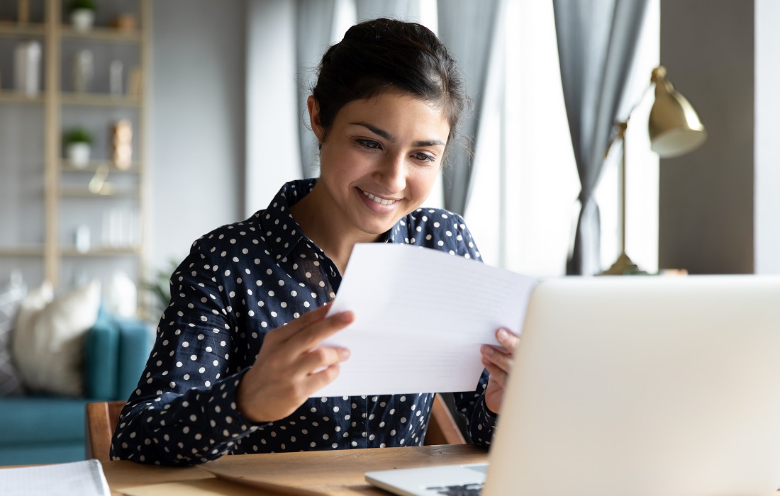 smiling-indian-woman-holding-reading-paper-letter-sit-at-table